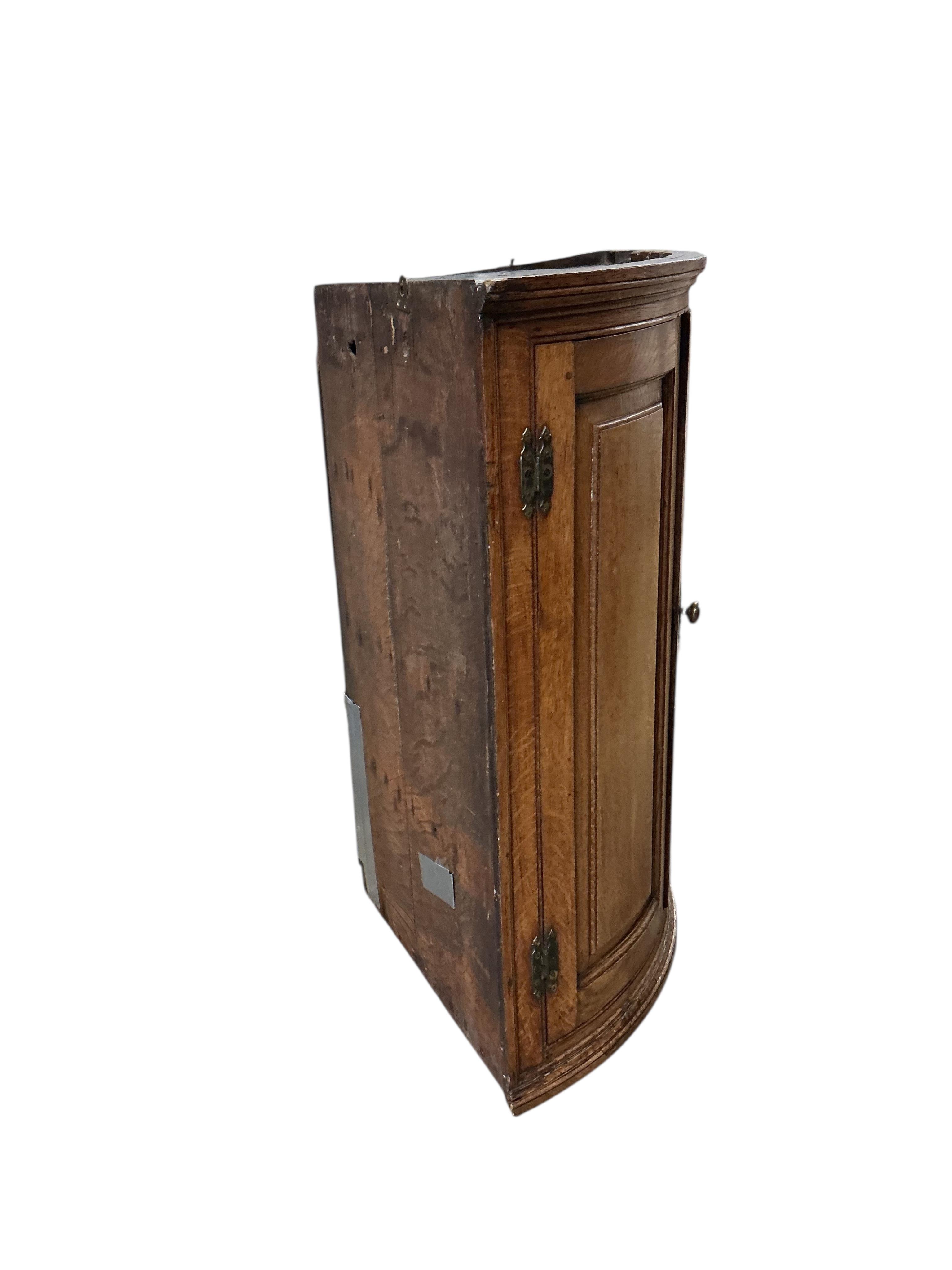 An early 19th century oak bowfront hanging corner cupboard, width 72cm, depth 49cm, height 97cm.